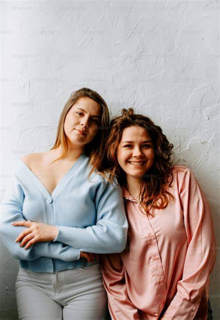 two women standing next to each other on a red carpet